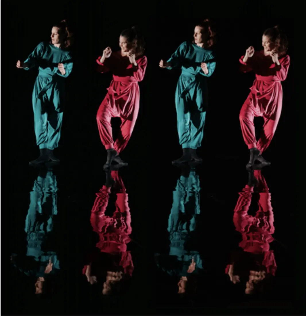 Lola dressed in a green jumpsuit and Eva in pink dancing next to each other, mirrored to show reflection on the floor